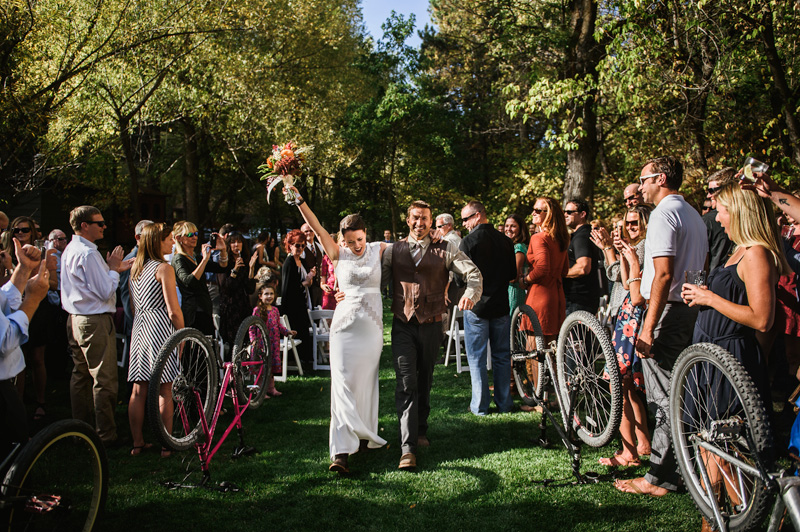 Adventure destination wedding celebration at A-Lodge Boulder Colorado with couple walking through guests holding bikes