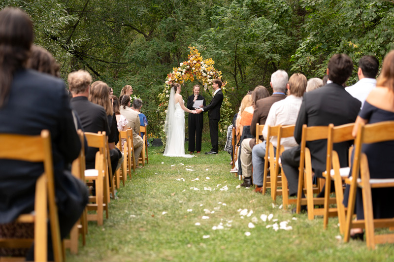 Outdoor destination wedding ceremony at A-Lodge Boulder Colorado with guests seated beside forested canyon