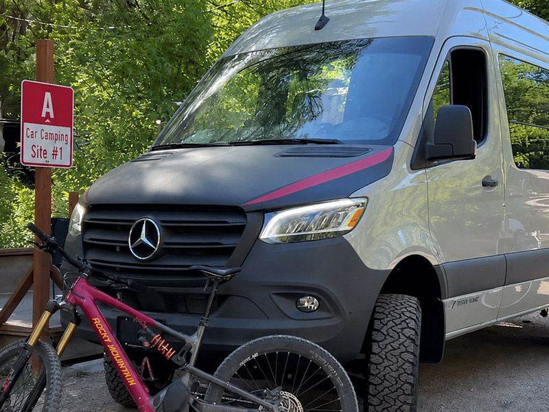 Van with a mountain bike leaning against it in a campsite in Boulder Colorado